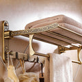 he Capri antique brass wall-mounted foldable bath towel rack with hooks.