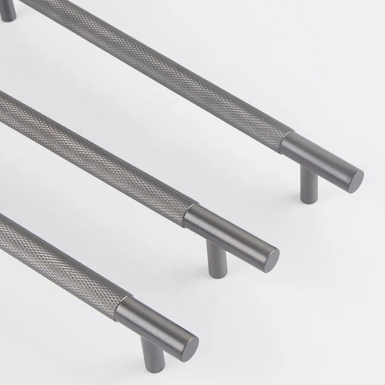 "Solid brass knurled cabinet handle with gunmetal finish and textured bar detail on terracotta fabric background"