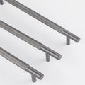 Three dark gray metal cabinet pulls with textured knurled grips and cylindrical end caps, arranged diagonally on a clean white background.