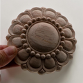 Wooden carvings with intricate patterns held by a hand on a white background