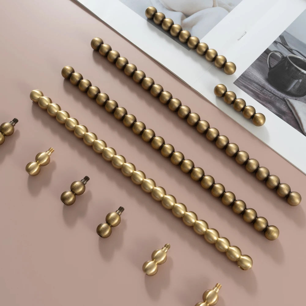 PERLA antique brass beaded ball cabinet handles and knobs in multiple sizes on pink background