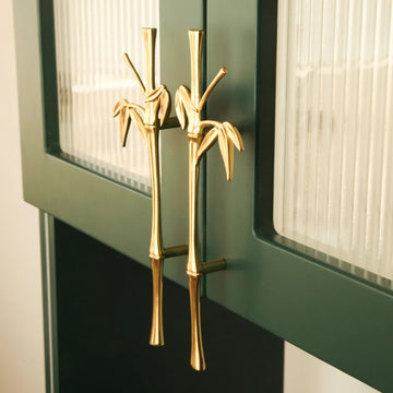 BAMBOO sculptural cast brass cabinet door handle in polished gold on dark green cabinet — botanical wardrobe pull