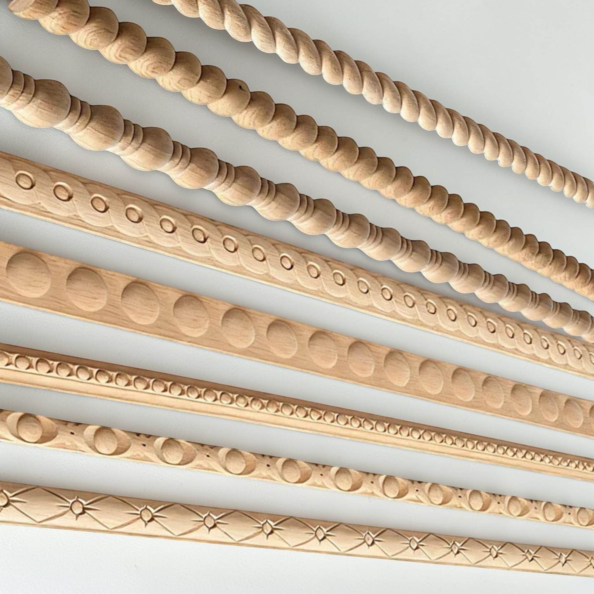 Unpainted carved wood line molding bars for edges and frames on a white background.